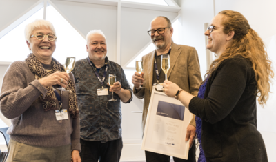 four people standing holding champagne glasses