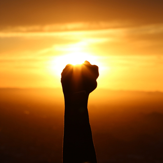 Reaching Goals Rised fist in front of the sundown